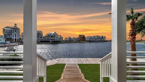 A wooden deck leading to a waterfront view with a sunset. - One More Day 310 DAR (Port Aransas)