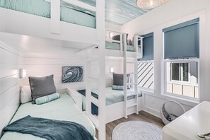 A room with bunk beds, a window, a white chair, and a woven basket. - Latin Vibe 312 SOU (Port Aransas)