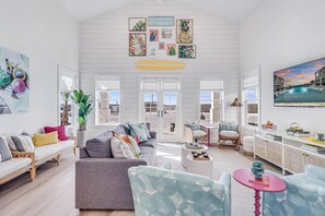 A spacious living room with a high ceiling, a large window, and a view of the outdoors. - Latin Vibe 312 SOU (Port Aransas)