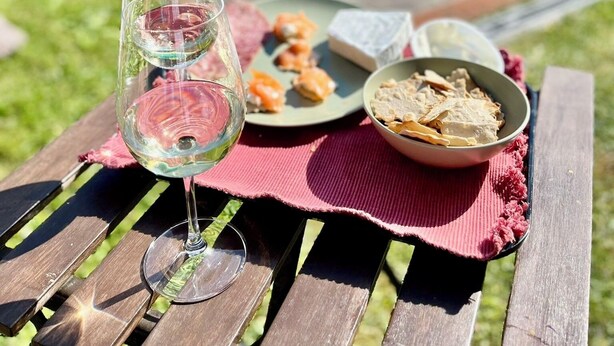 A picnic setup with a glass of white wine, a plate of food, and a bowl of crackers on a wooden table. - Super Villa met 5 Slaapkamers, max 10 Pers, Groot Privé Zwembad & Heerlijke Tuin (Monsagrati)