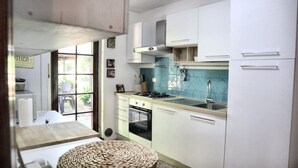 A compact kitchen with white cabinets, a gas stove, an oven, and a sink with a blue backsplash. - Super Villa met 5 Slaapkamers, max 10 Pers, Groot Privé Zwembad & Heerlijke Tuin (Monsagrati)
