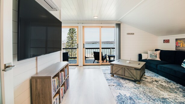 A modern living room with a flat-screen TV, a bookshelf, a coffee table, and a dark-colored sofa.