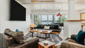 A modern living room with leather sofas, a wooden coffee table, and a large TV mounted on the wall.