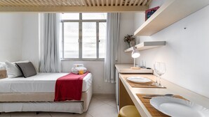 A modern bedroom with a bed, a desk, and a window.