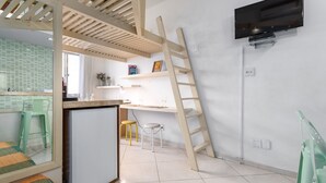 A modern kitchen with a built-in refrigerator, a wooden ladder, and a TV mounted on the wall.