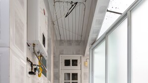 A narrow hallway with tiled walls and floor, a door with frosted glass panels, and a ceiling with exposed beams and a hanging light fixture.