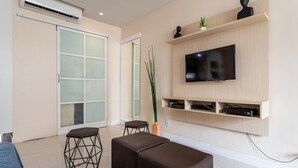 Una sala de estar moderna con un televisor de pantalla plana, estanterías de madera y un amplio ventanal corredero.