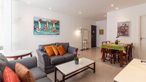 A modern living room with a grey sofa, a coffee table, and a dining area with a green tablecloth. - 7 minutes from Ipanema beach | BT201 (Rio de Janeiro)