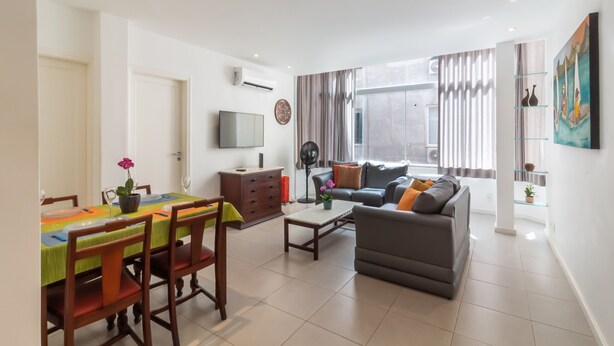 A modern living room with a sofa, coffee table, and dining area with chairs and a table. - 7 minutes from Ipanema beach | BT201 (Rio de Janeiro)