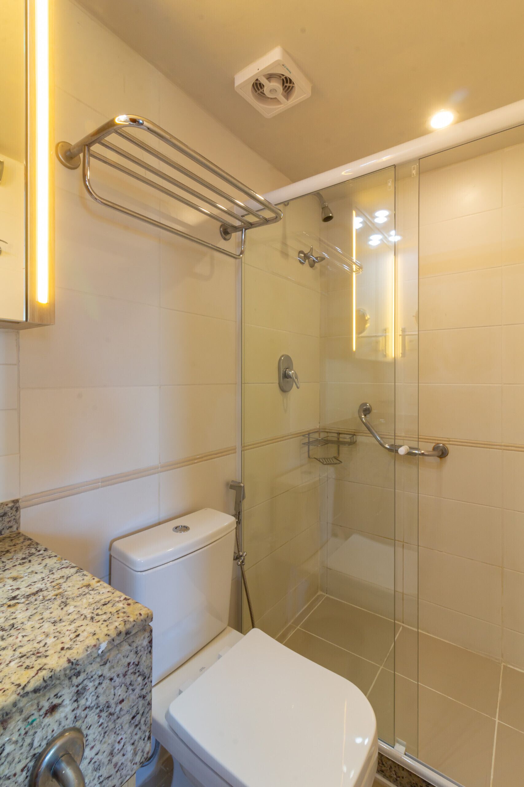 Ein Badezimmer mit einer gläsernen Duschkabine, einer weißen Toilette und einer Arbeitsplatte aus Granit.