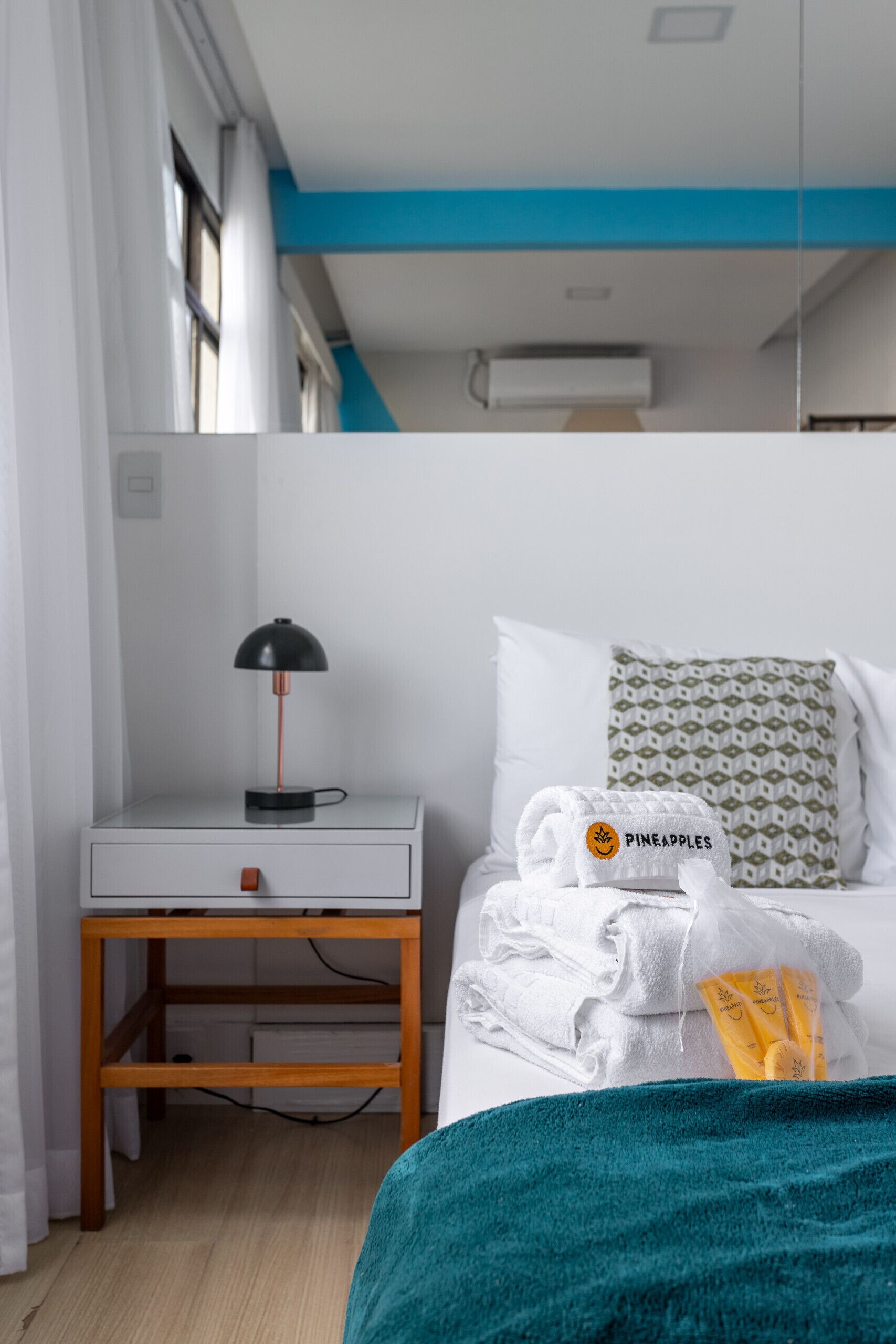 Ein Hotelzimmer mit einem Bett, einem Nachttisch mit Lampe, einem Fenster und einer Wand-Klimaanlage.