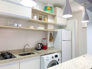 Eine moderne Küche mit Einbauwaschmaschine, Kühlschrank, Spüle und einer Arbeitsplatte mit Wasserkocher und Mixer.