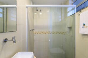 Ein modernes Badezimmer mit einer Duschkabine, einem weißen Waschbecken und einem Handtuchhalter mit Handtuch.