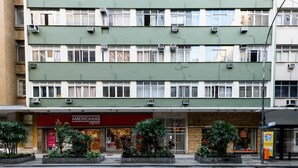 A multi-story building with air conditioning units, a storefront with a red sign, and potted plants in front. - Peace in Copacabana | Forest view | BR1009 (Rio de Janeiro)