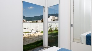 A modern room with a sliding glass door leading to a balcony with a view of mountains and a cityscape. - Penthouse in Ipanema | Christ View | MQC502 (Rio de Janeiro)