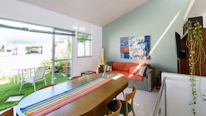 A dining area with a wooden table, chairs, and a colorful placemat. There is a sofa with cushions and a painting on the wall. - Penthouse in Ipanema | Christ View | MQC502 (Rio de Janeiro)