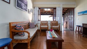 A living room with wooden furniture, a sofa, chairs, a coffee table, and a TV. - Apart Hotel  | BUZ215 (Armação dos Búzios)