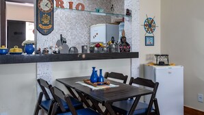 A kitchen with a tiled backsplash, a clock, and a refrigerator. - Apart Hotel  | BUZ215 (Armação dos Búzios)