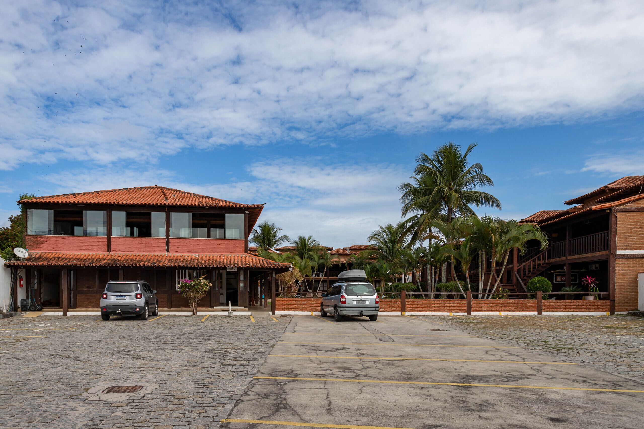 A building with a red-tiled roof and a parking area with two cars.