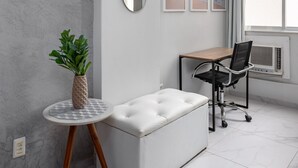 A modern room with a white sofa, a small round table with a plant, a desk with a chair, and a large window with curtains. - Style in Copacabana | Near the beach | BR403 (Rio de Janeiro)