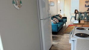 A kitchen with a stove, refrigerator, and dining area with chairs and a table.