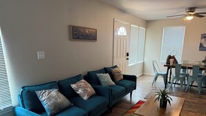 A living room with a teal sofa, a coffee table, and a colorful rug.