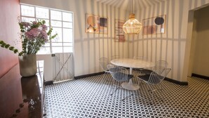 A dining area with a round table and wire chairs, a patterned floor, and a vase with flowers. - Departamentos Versalles (Mexico City)