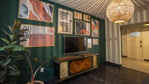 A room with a dark wood floor, a television on a wooden cabinet, and a hanging light fixture. - Departamentos Versalles (Mexico City)
