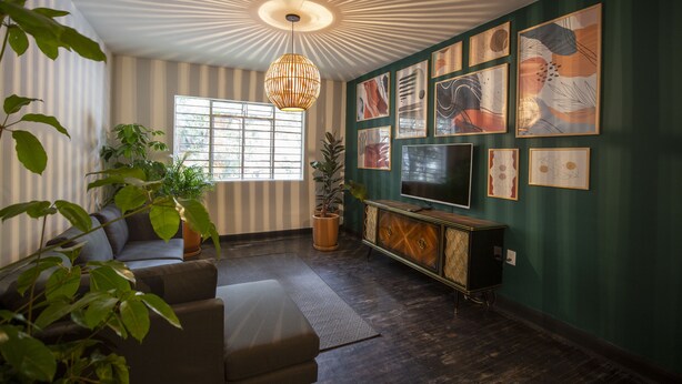 A living room with a sofa, a coffee table, a TV, and a decorative ceiling light. - Departamentos Versalles (Mexico City)