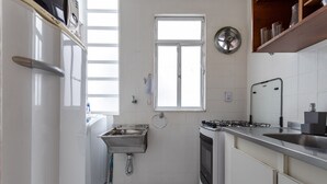 Eine kompakte Küche mit Einbauofen, Spüle aus Edelstahl und Fenster.
