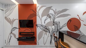 A modern room with a TV mounted on the wall, a black shelf, and a wooden chair.