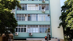 Ein mehrstöckiges Gebäude mit Klimaanlagen, einem sichtbaren Schaufenster und einer Menschenmenge.