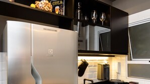 Una cocina moderna con refrigerador de acero inoxidable, armarios negros y piso con estampado blanco y negro.