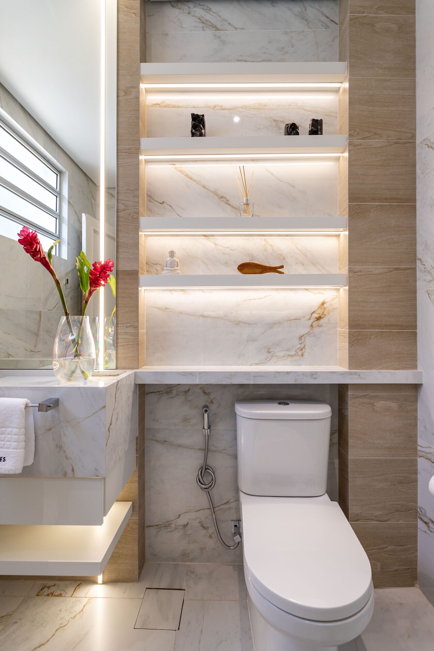 Een moderne badkamer met een marmeren wastafel, toilet en planken met decoratieve objecten.
