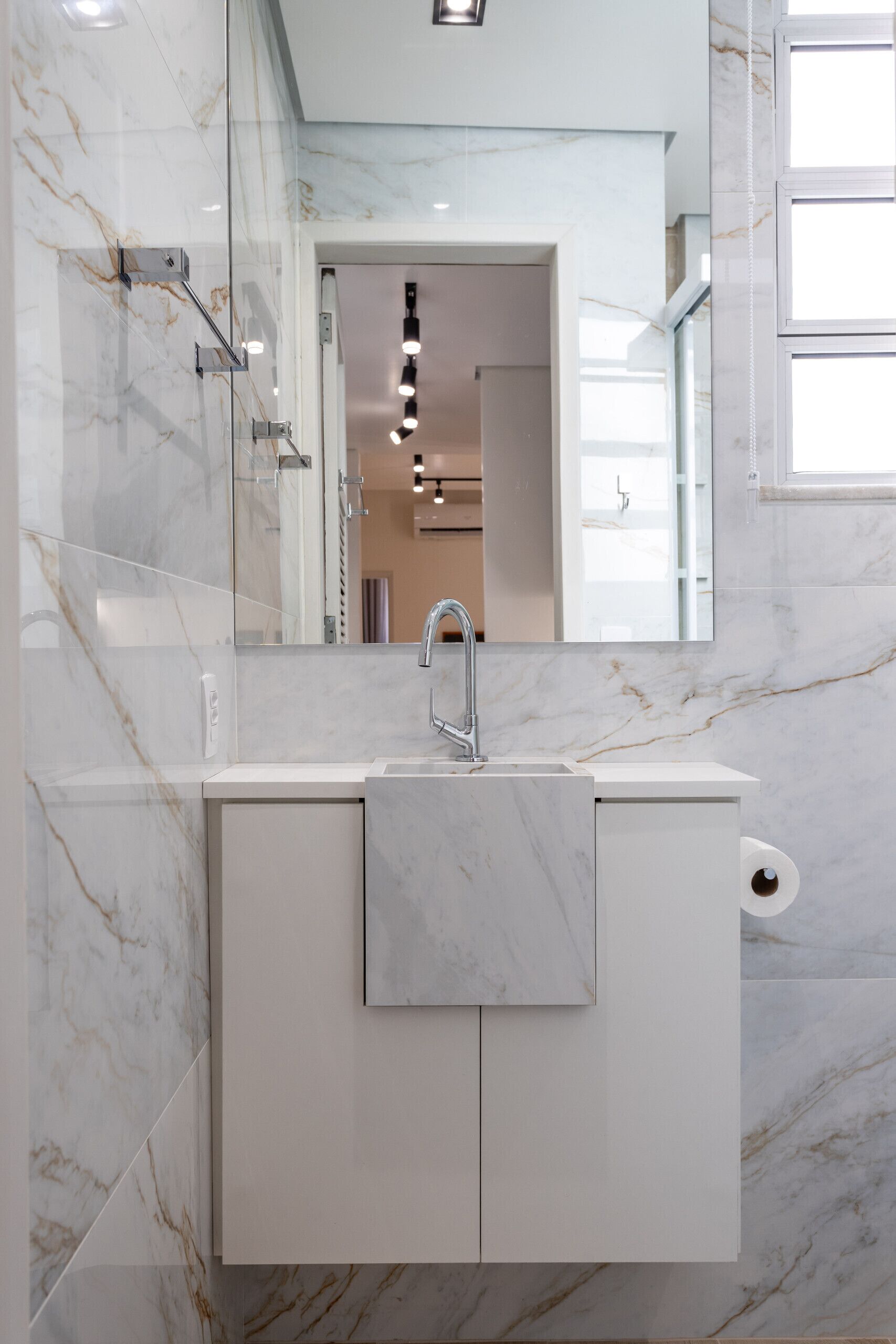 Un baño moderno con un lavabo de mármol, un espejo grande y vistas a la habitación contigua.