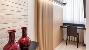 A modern interior with a wooden wall, a black countertop with two red vases, a wooden slatted panel, a black chair, and a desk with a window. - Perfect for couples in Ipanema | VP802 (Rio de Janeiro)