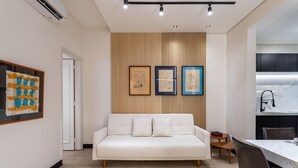 A modern living room with a white sofa, a small wooden table, and framed artwork on the wall. - Perfect for couples in Ipanema | VP802 (Rio de Janeiro)