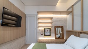 A modern hotel room with a flat-screen TV mounted on the wall, a bed with white linens, a green throw blanket, a wooden headboard, and a framed picture on the wall. - Perfect for couples in Ipanema | VP802 (Rio de Janeiro)