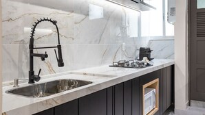 A modern kitchen with dark cabinetry, a white marble countertop, and a stainless steel sink. - Perfect for couples in Ipanema | VP802 (Rio de Janeiro)