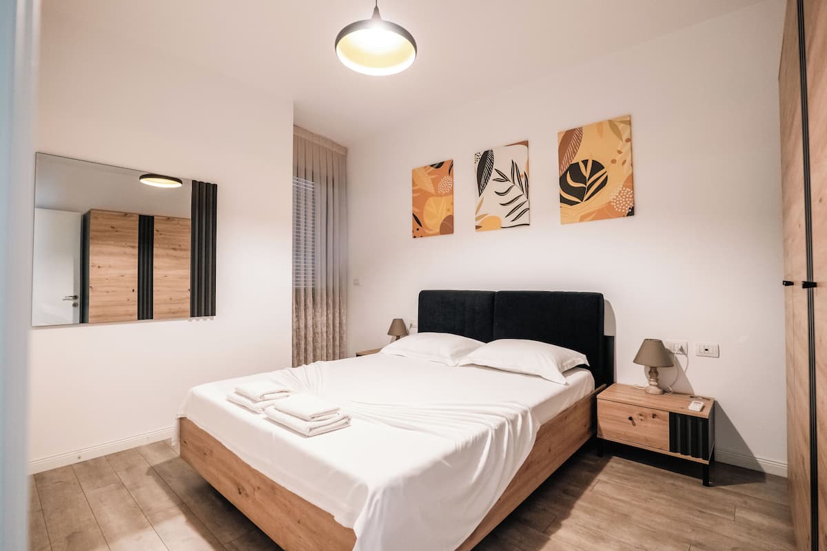 Une chambre à coucher avec un lit, une table de chevet, une lampe et des œuvres d’art murales.