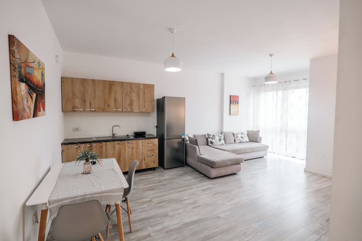 Une cuisine moderne avec des meubles en bois, un réfrigérateur et une table à manger avec des chaises.