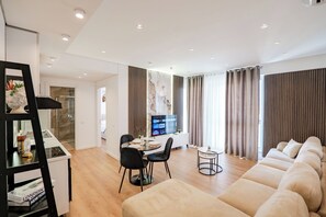 A modern living room with a sofa, dining area, and a TV.