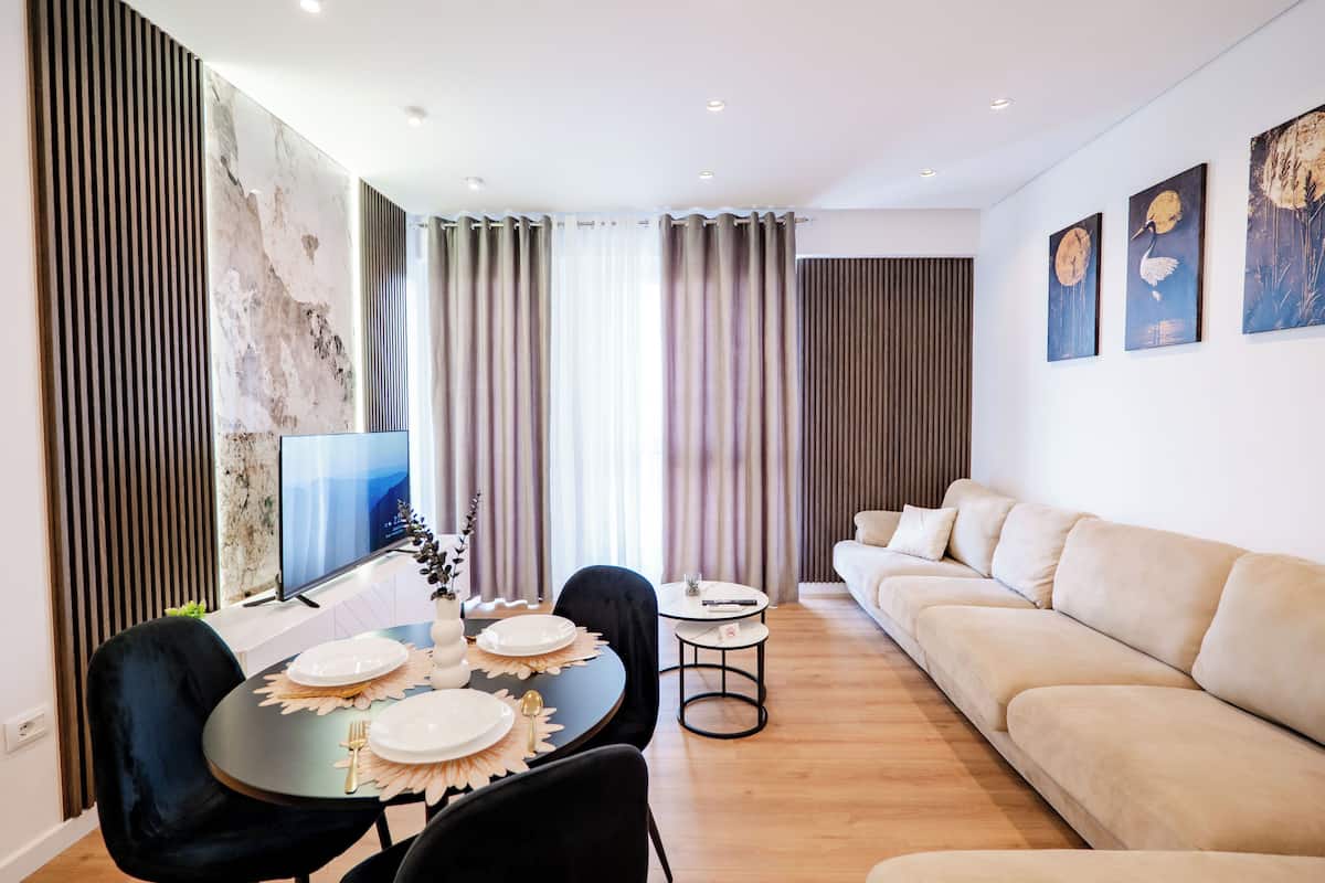 Un salon moderne comprenant un coin repas, un canapé et des œuvres d’art accrochées au mur.
