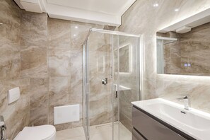 Deluxe appartement | Badkamer | Een douche, een regendouche, een haardroger, pantoffels