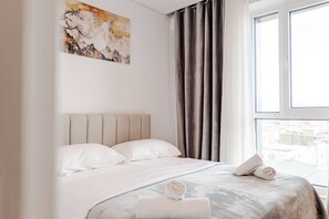 Ein Hotelzimmer mit einem Bett, einem Bild an der Wand und einem Fenster mit Vorhängen.