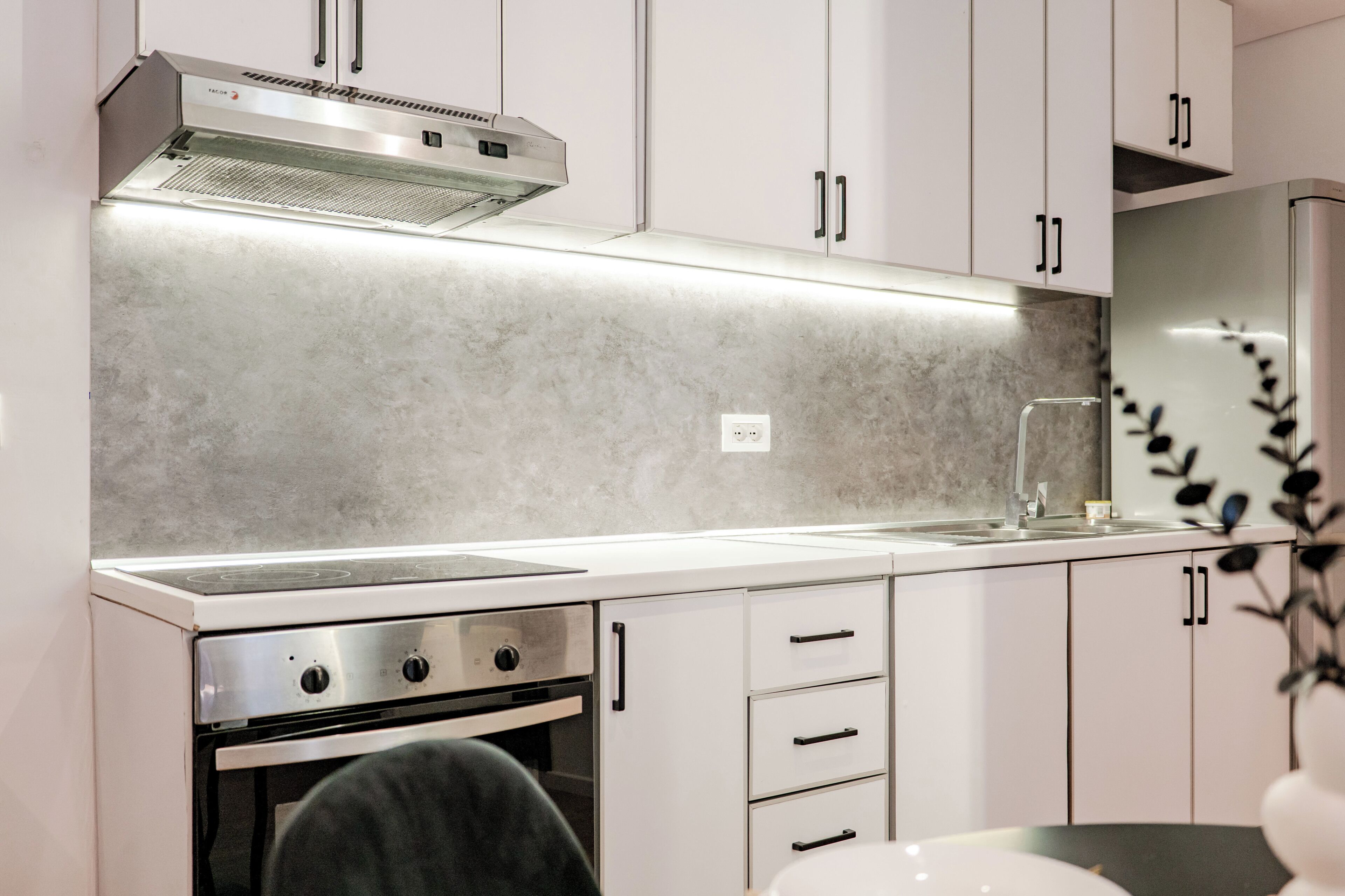 A modern kitchen with white cabinets, a stainless steel range, and a built-in oven.