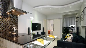 Una cocina moderna con una isla de vidrio, electrodomésticos de acero inoxidable y un televisor de pantalla plana.
