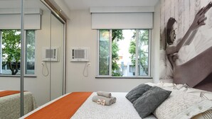 Una habitación de hotel moderna con una cama grande, una puerta de cristal y dos ventanas.