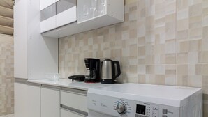 Eine kompakte Küche mit integriertem Waschtrockner, einer Kaffeemaschine und einer Mikrowelle.