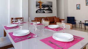 Ein Essbereich mit einem weißen Tisch, gedeckt für sechs Personen, rosa Untersetzern und roten Pendelleuchten.